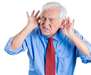 A close-up portrait of an elderly executive looking unhappy and annoyed,having trouble hearing his opponent, during unpleasant conversation, isolated on a white background . Hearing aid.
