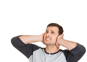 Closeup portrait of young man, student, worker, employee covering his ears from loud noise, having headache isolated on white background. Conflict resolution. Negative human emotions, face expressions