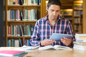 Concentrated mature male student using tablet PC at desk in the library