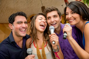 Group of friends having fun karaoke singing at the bar
