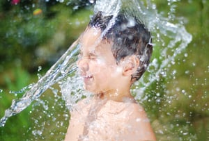 Little cute kid getting splashed by a stream of water in his face