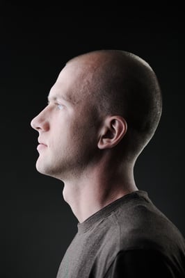 Profile of white bald man in his twenties in dark