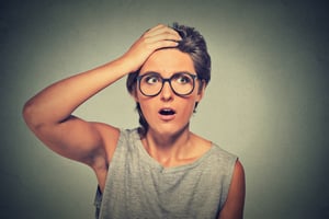 Surprise astonished woman. Closeup portrait woman with glasses looking surprised in full disbelief wide open mouth isolated grey wall background. Human emotion facial expression body language.