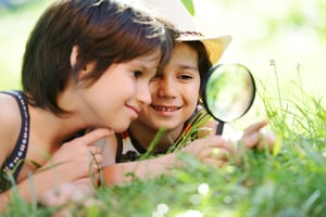 Two boys with magnifying glass outdoors