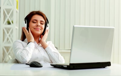 Young beautiful businesswoman listening music in headphones at office